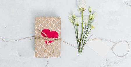 Cadeautje met een hartje erop met witte bloemen ernaast