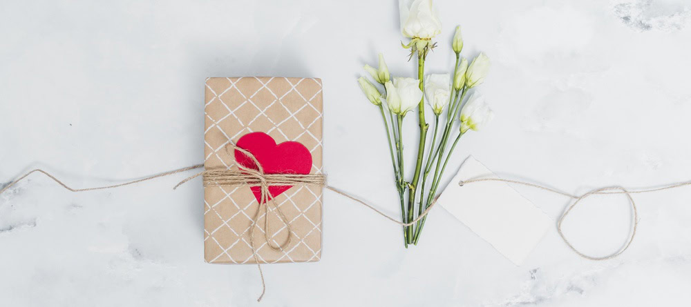 Cadeautje met een hartje erop met witte bloemen ernaast