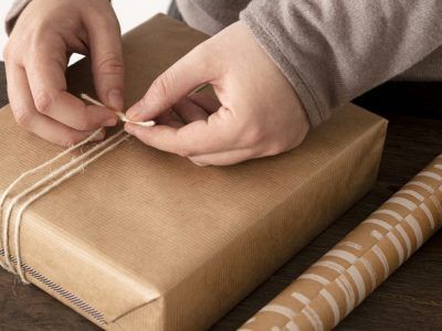 Persoon pakt een cadeau in met touw