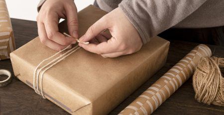 Persoon pakt een cadeau in met touw