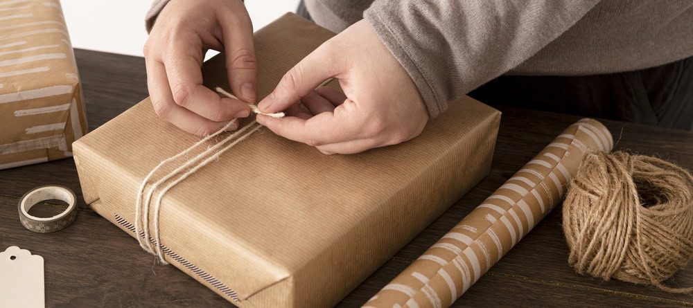 Persoon pakt een cadeau in met touw