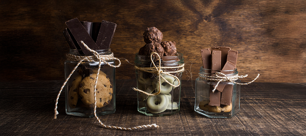 Chocolade bedankjes en dag van de chocolade Drie glazen potten met verschillende lekkernijen.